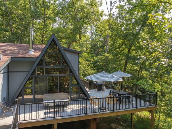 Une cabane moderne dotée d’une terrasse, de grandes fenêtres et de mobilier d’extérieur.