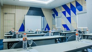 Une salle de conférence équipée de tables, de chaises, de bouteilles d’eau et de verres.