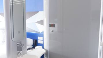 A modern bathroom with a white sink, mirror, and a glass shower enclosure.