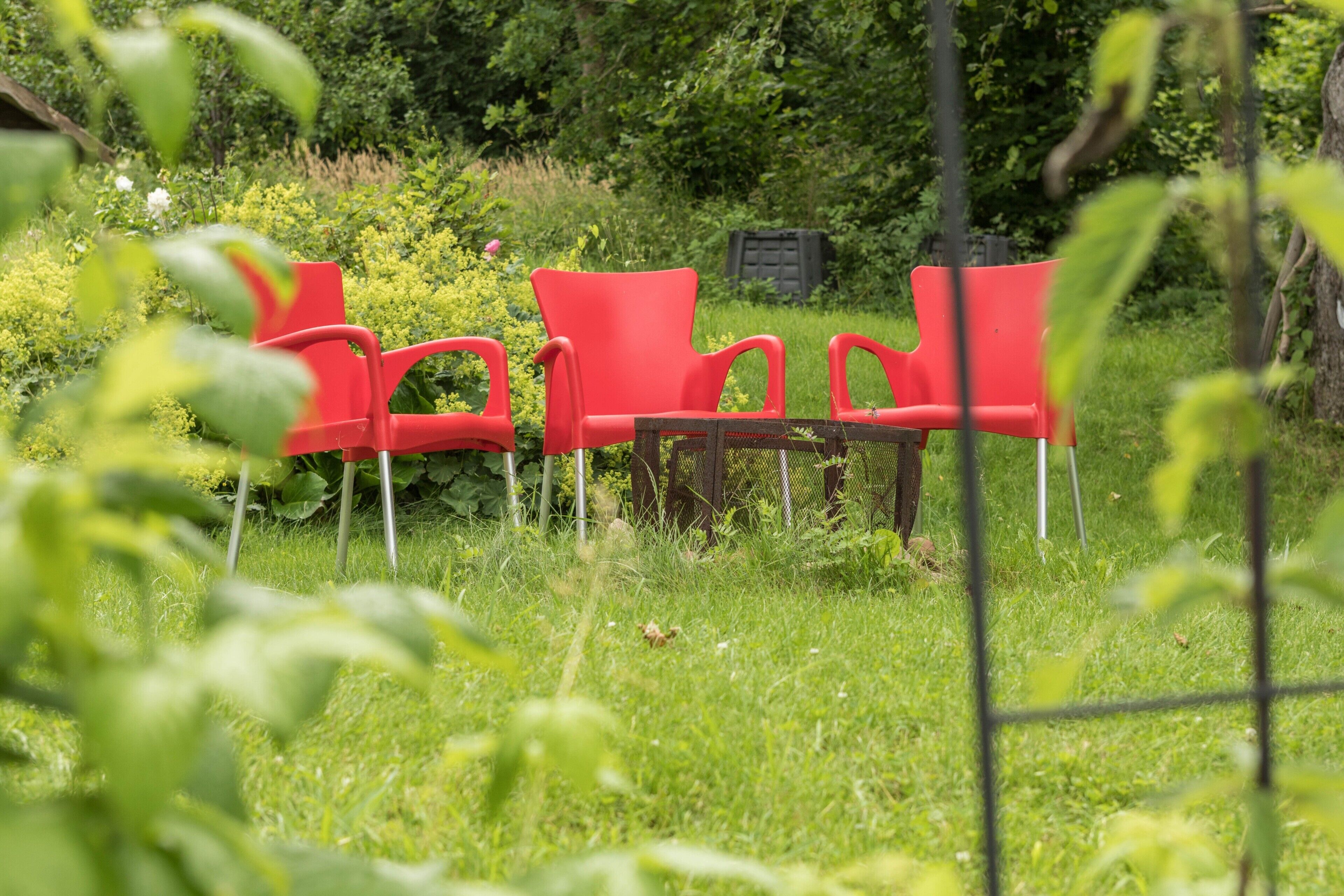Ein Garten mit roten Stühlen und einem Holztisch.