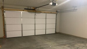 Een garage met een betonnen vloer en een witte garagepoort.