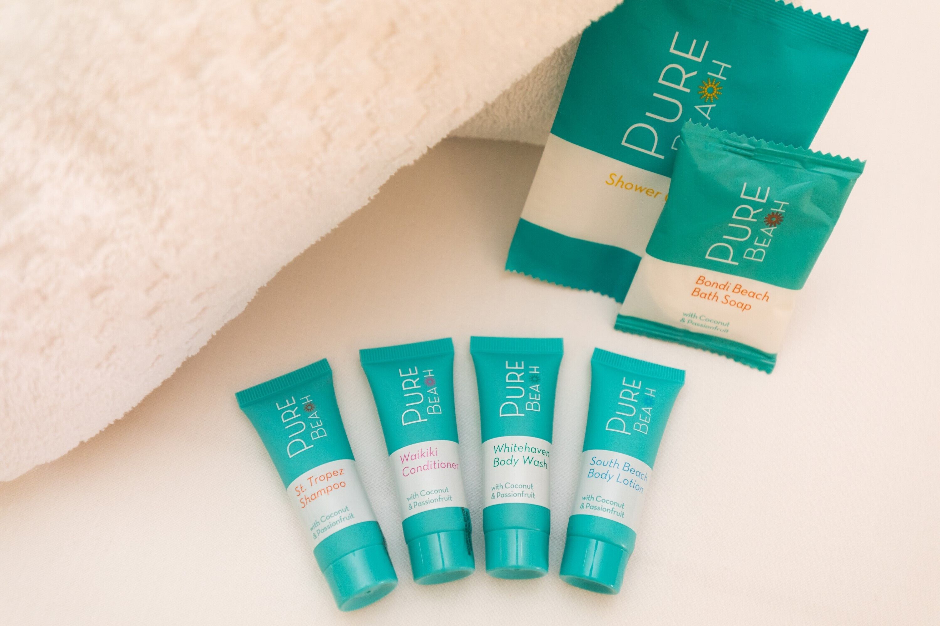 Five bottles of Pure Beach body wash and conditioner, a towel, and a shower bag.