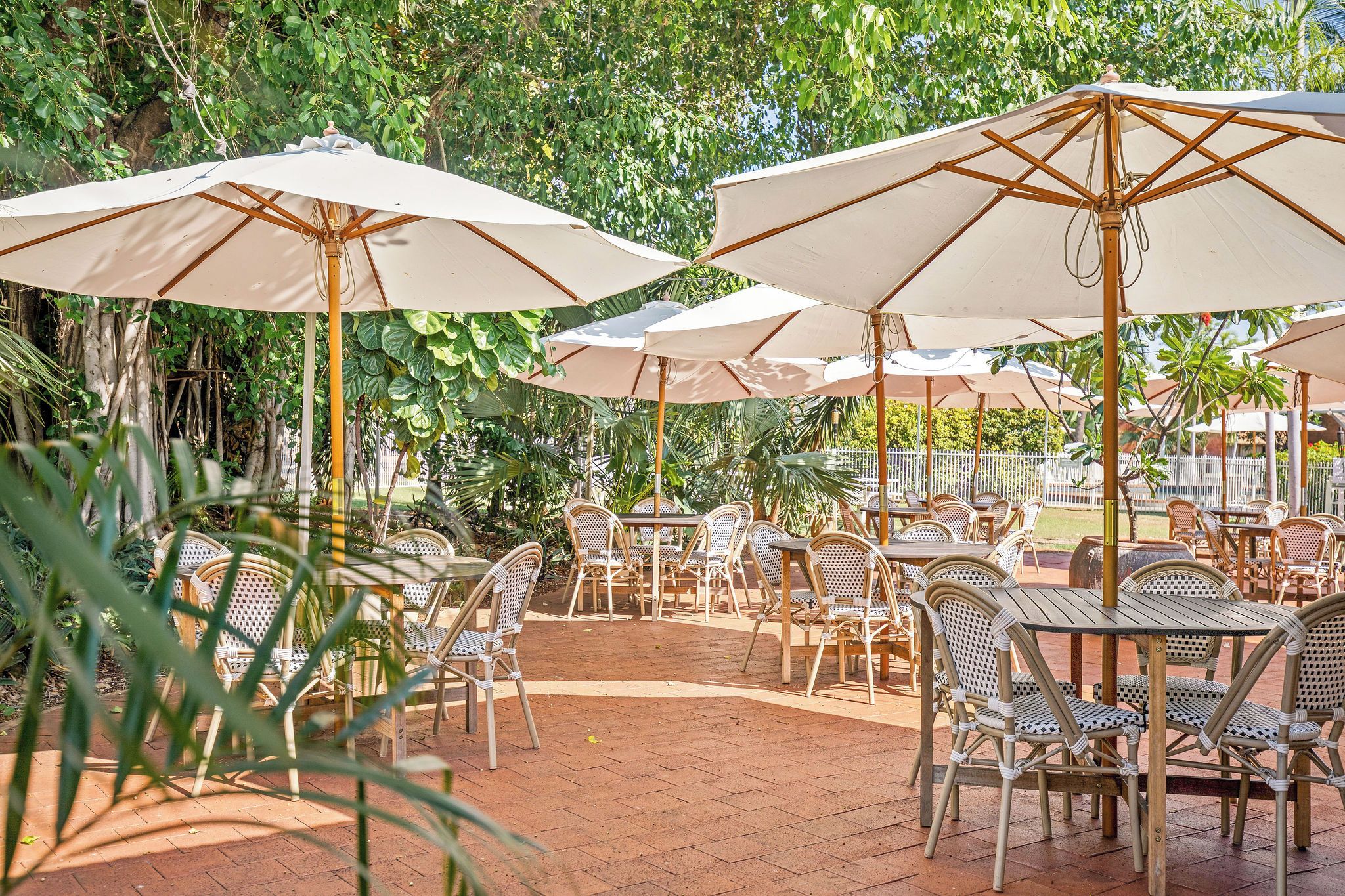 An outdoor patio with tables and chairs, shaded by large umbrellas.