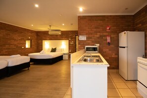 A compact hotel room with two beds, a kitchenette, and a brick wall. - Contour Hotel Katherine (Katherine East)