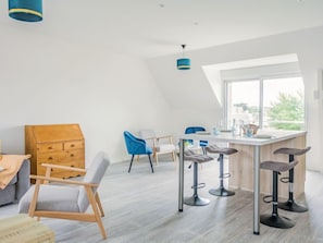 A modern kitchen with a bar area, high ceilings, and a large window providing a view of the outdoors.