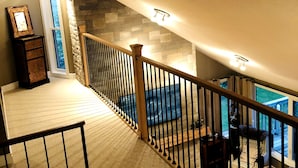 A staircase with a wooden railing leading to a balcony. - Top Rated Waterfront Cottage + Sauna | Beach | Private Dock (Georgian Bluffs)