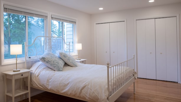 Un dormitorio con cama, lámparas de noche, ventana y armario.
