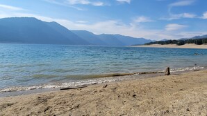 A beach with clear water, a sandy shore, and mountains in the background.