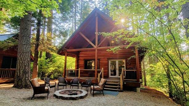 A log cabin with a porch, outdoor seating, and a fire pit.