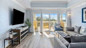 Un salón amplio con televisor de pantalla plana, un sofá, una mesa de centro y un balcón con vistas.