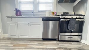 A kitchen with white cabinets, a stainless steel dishwasher, and an oven.