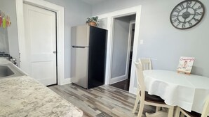A kitchen with a marble countertop, a refrigerator, and a dining table with chairs.