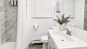 A modern bathroom with a bathtub, toilet, and sink.