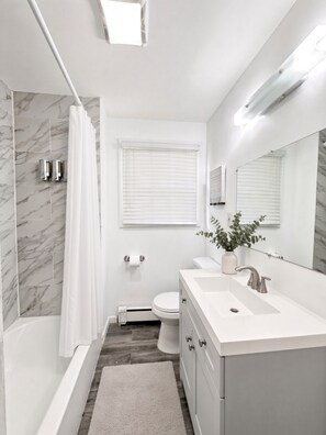 A modern bathroom with a bathtub, toilet, and sink. - Cedar Brook Manor - Rutgers | NYC | Jersey Shore - Union County - EXTENDED STAY (Plainfield)