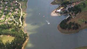 Vista aérea de un lago con una pequeña isla que tiene edificios y un muelle.