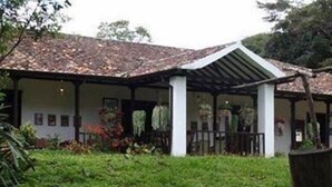 Un espacio al aire libre cubierto con techo de tejas, rodeado de vegetación.