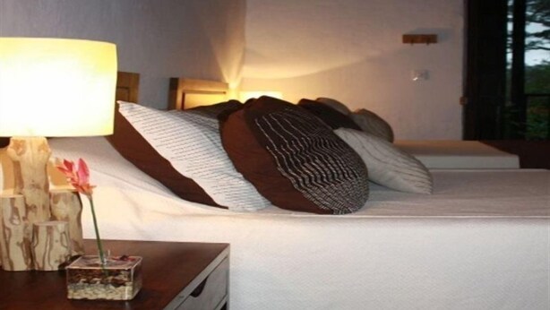 Una habitación de hotel con una cama, una mesita de noche con lámpara y un objeto decorativo pequeño.