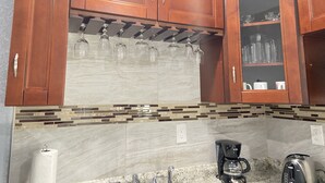 A kitchen with wooden cabinets, a marble backsplash, and a coffee maker. - Bahía Heaven (Tampa)