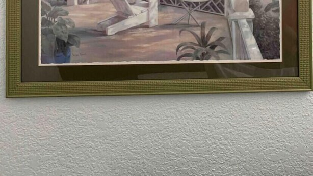 A framed painting of a tropical outdoor seating area with palm trees, a pool, and a view of the ocean. - Bahía Heaven (Tampa)