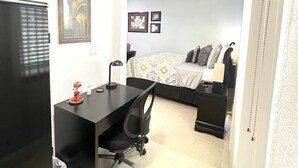 A compact bedroom with a bed, a desk, and a chair. - Bahía Heaven (Tampa)