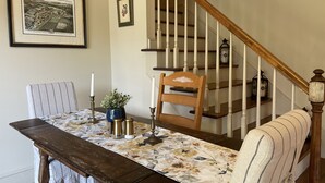 Un comedor con una mesa de madera, sillas y una escalera.
