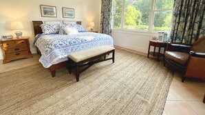 Un dormitorio con una cama grande, una mesita de noche, una silla y una ventana con cortinas.