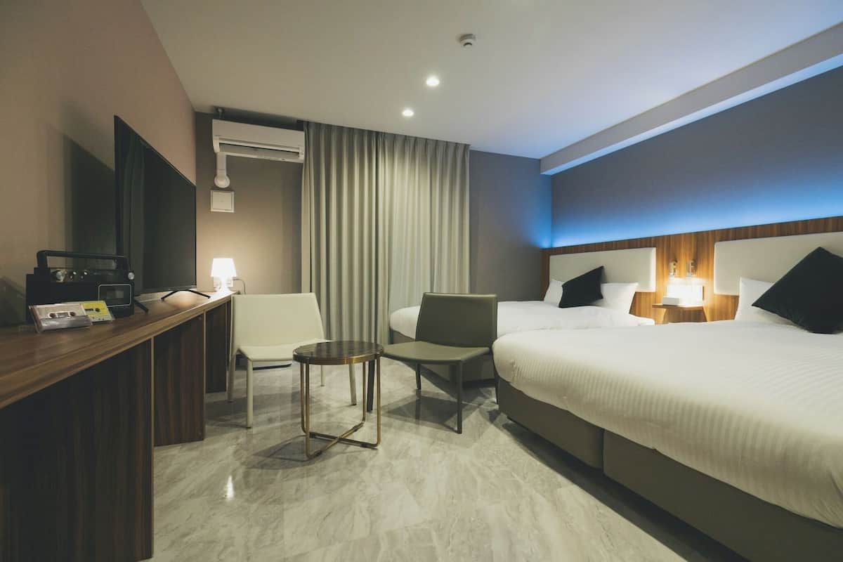 Une chambre d’hôtel avec un lit, un bureau doté d’une lampe, une chaise et une petite table.