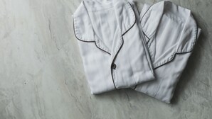 Une chemise blanche soigneusement pliée, avec un bouton et un col, posée sur un sol en marbre.