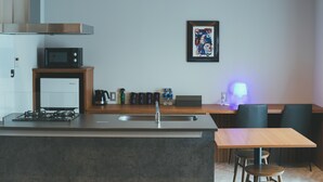 Une cuisine moderne équipée d’une cuisinière, d’un four à micro-ondes et d’un évier intégrés. Un coin repas avec une table et des chaises est également disponible.