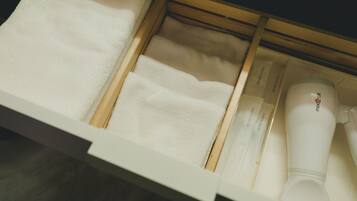 A drawer with neatly folded towels and a hairdryer.