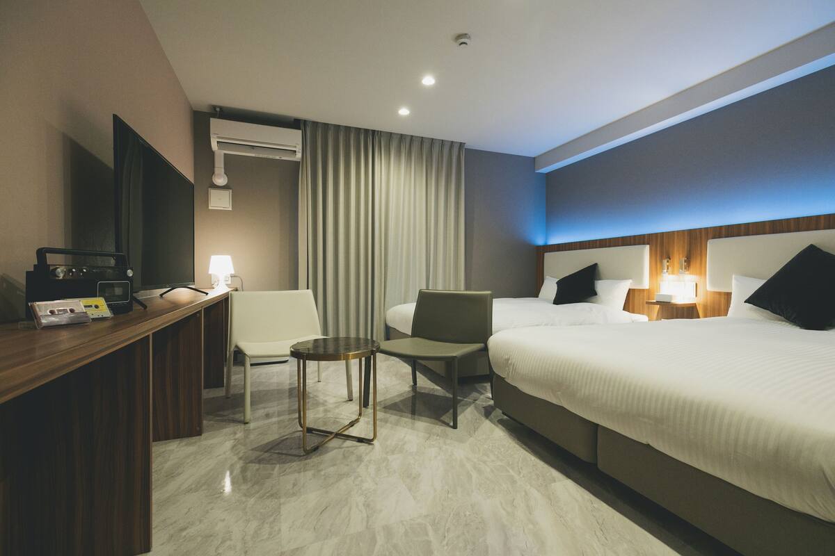 Ein Hotelzimmer mit einem Bett, einem Schreibtisch mit Computer, einem Stuhl und einem kleinen Tisch.