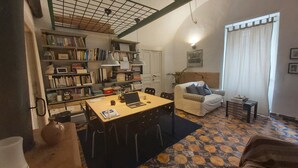A cozy living room with a sofa, a coffee table, and a bookshelf filled with books. - Room-dimora Aganoor Business Suite (Cava de' Tirreni)