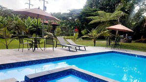 A rectangular swimming pool with blue mosaic tiles, surrounded by lounge chairs and tables. - Posada La Querencia (Xico)