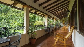 A covered outdoor area with wooden benches and tables, surrounded by potted plants and a view of lush greenery. - Posada La Querencia (Xico)