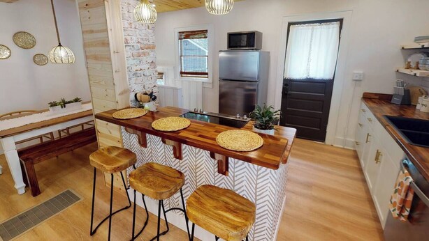 A modern kitchen with a central island, bar stools, a refrigerator, and a microwave.
