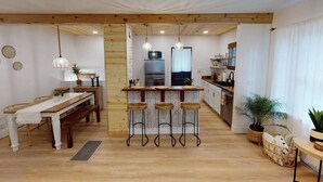 A modern kitchen with a central island, bar stools, and a dining area with a bench.
