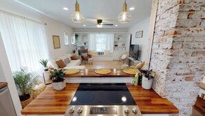 A modern kitchen with a large stove, wooden countertops, and pendant lights.