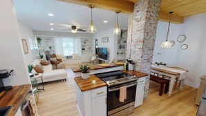 A modern kitchen with a central island, wooden countertops, and a built-in oven.