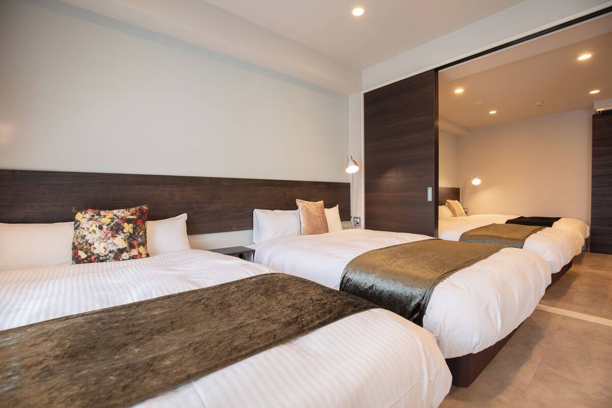Een hotelkamer met drie bedden, een grote spiegel en een houten hoofdbord.