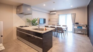 A modern kitchen with a central island, built-in oven, and a dining area with a table and chairs. - HOTEL SO SUMIYOSHI (Fukuoka)
