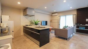 A modern kitchen with a central island, built-in appliances, and a flat-screen TV. - HOTEL SO SUMIYOSHI (Fukuoka)