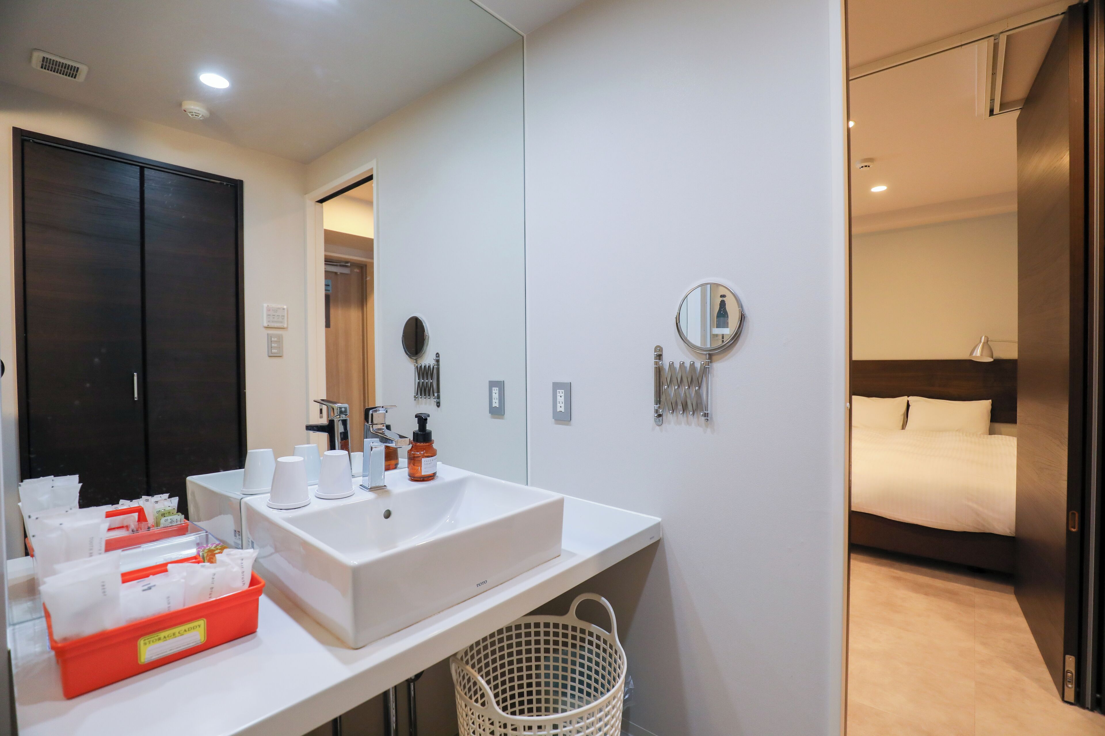 A modern bathroom with a large sink, mirror, and toiletries.
