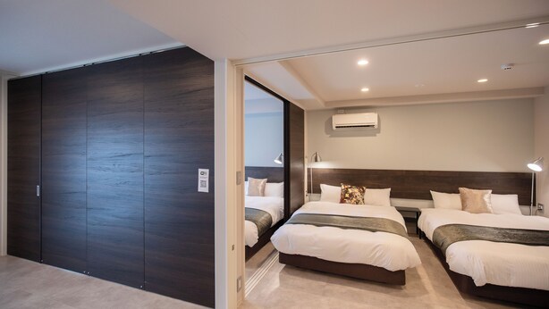 A modern hotel room with two beds, a dark wood wardrobe, and an air conditioning unit on the wall. - HOTEL SO SUMIYOSHI (Fukuoka)