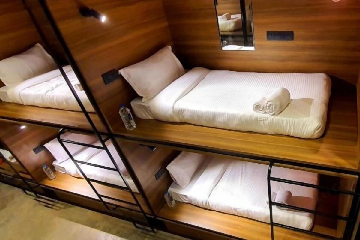 A hotel room with bunk beds, wooden walls, and a small window.