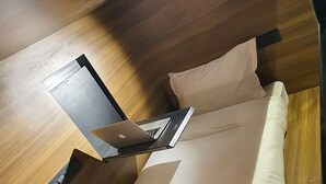 Un interior de madera con una cama, una computadora portátil y una regleta de enchufes.