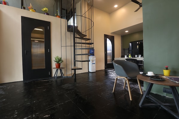 A modern interior with a staircase, a dining area with a table and chairs, and a kitchen area.
