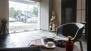 Una habitación con vista a la calle, una mesa con un libro, una taza y una planta en maceta.