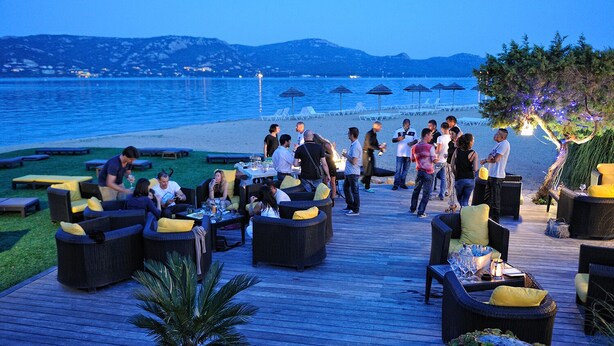 A deck area with outdoor seating and a view of the sea. - Beautiful waterfront villa (Porto-Vecchio)