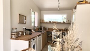 A compact kitchen with a wooden countertop, a washing machine, a stove, and a window providing natural light. - Beautiful waterfront villa (Porto-Vecchio)