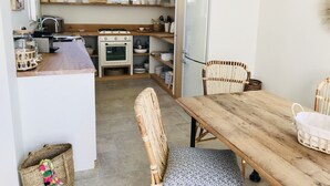 A compact kitchen with a wooden table, wicker chairs, and a refrigerator. - Beautiful waterfront villa (Porto-Vecchio)